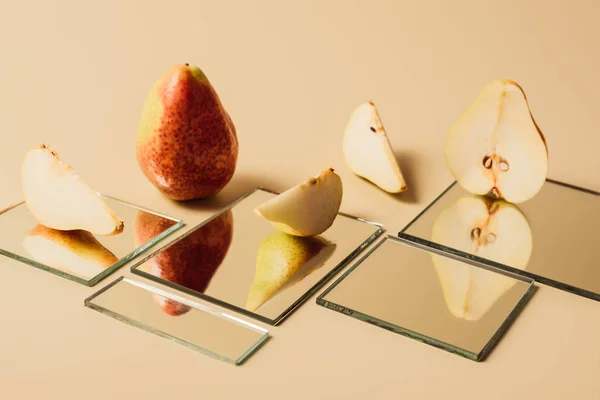 Yellow pears reflecting in mirrors on beige tabletop — Stock Photo