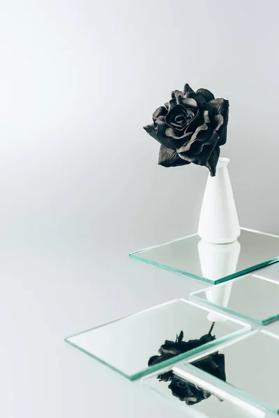 Une rose noire dans un vase réfléchissant dans des miroirs isolés sur du blanc — Photo de stock