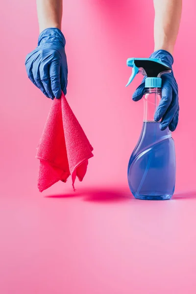 Imagem cortada de limpador feminino segurando líquido de limpeza e pano, fundo rosa — Fotografia de Stock