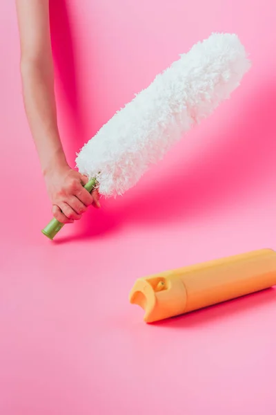 Cropped image of woman holding white duster near spray can, pink background — Stock Photo