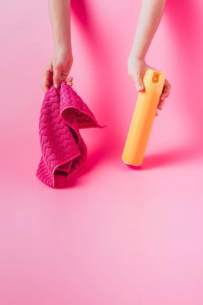 Imagem cortada de mulher segurando lata de pulverização e pano, fundo rosa — Fotografia de Stock