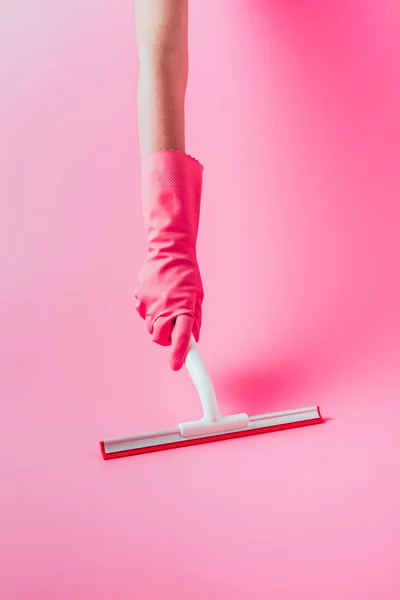 Imagen recortada de la mujer en el piso de limpieza de guantes de goma por la escobilla, fondo rosa - foto de stock