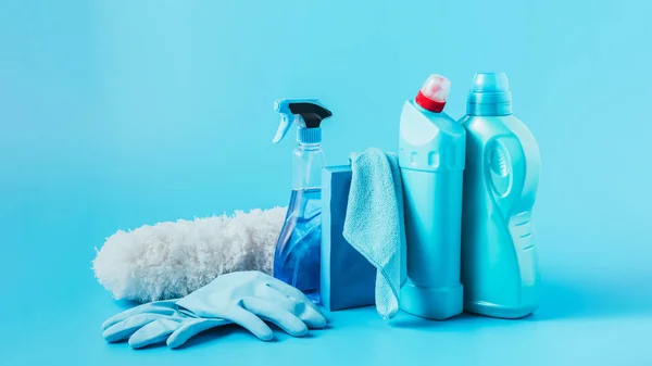 Close up view of duster, rubber gloves, cleaning fluids, washing powder, rag and laundry liquid on blue background — Stock Photo