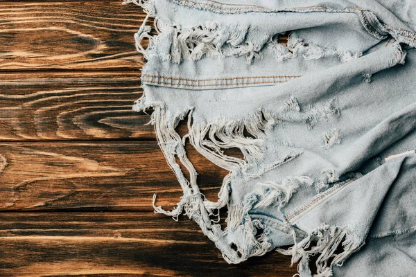 Верхний вид светлого джинсового текстиля на деревянную поверхность — стоковое фото
