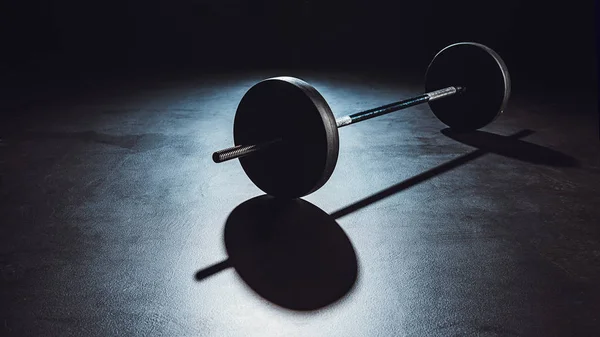 Close up view of barbell on floor with shadow at gym, black background — Stock Photo