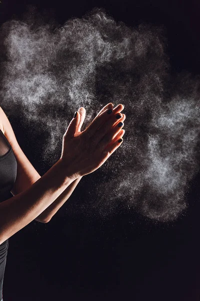 Image recadrée de sportive étalant de la poudre de craie dans les mains, fond noir — Photo de stock