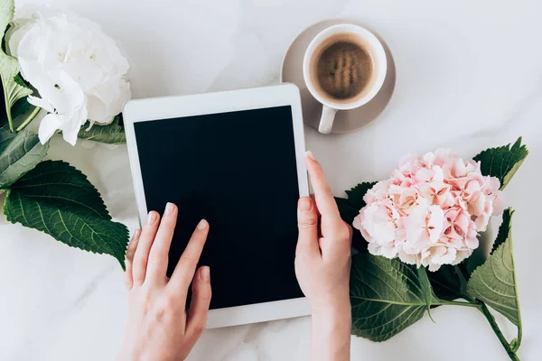 Vista ritagliata della donna utilizzando tablet digitale con schermo bianco sul tavolo con caffè espresso e fiori di hortensia — Foto stock