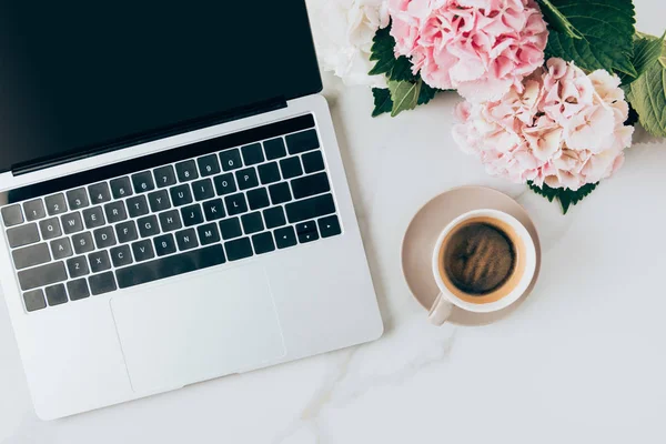 Plat laïc avec ordinateur portable, tasse à café et fleurs d'hortensia sur la surface du marbre — Photo de stock
