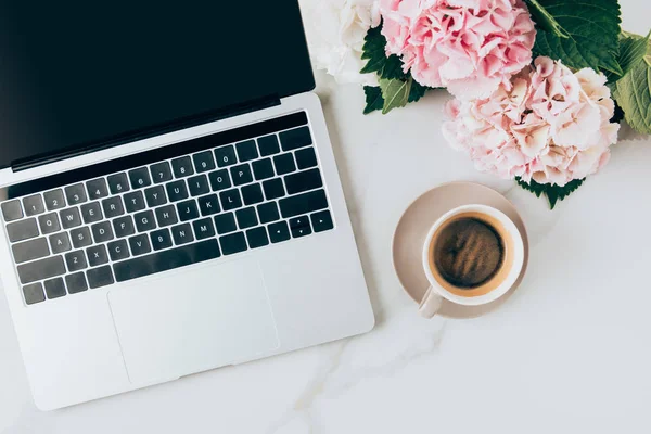 Plano con portátil, taza de café y flores de hortensia en la superficie de mármol - foto de stock