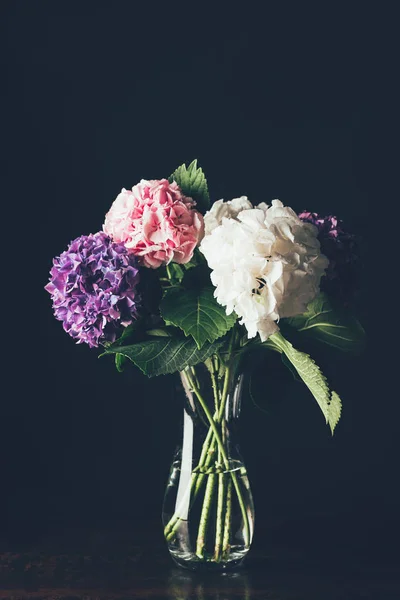 Flores de hortensia rosa, blanca y púrpura en jarrón de cristal, sobre negro — Stock Photo