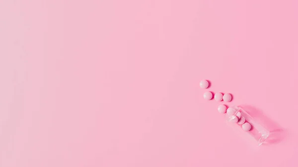 Top view of pink medicines spilled from bottle on pink surface — Stock Photo