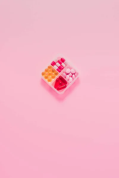 Draufsicht auf Kunststoffbehälter mit verschiedenen sortierten Medikamenten auf rosa — Stockfoto