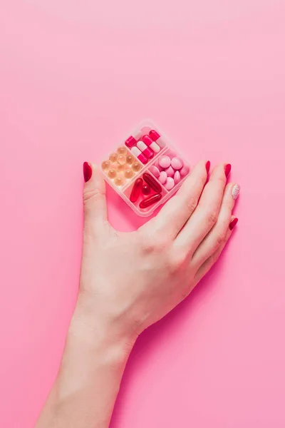 Tiro recortado de mulher segurando recipiente de plástico para medicamentos em rosa — Fotografia de Stock