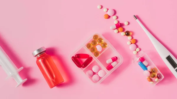 Top view of different medicines and electric thermometer on pink surface — Stock Photo