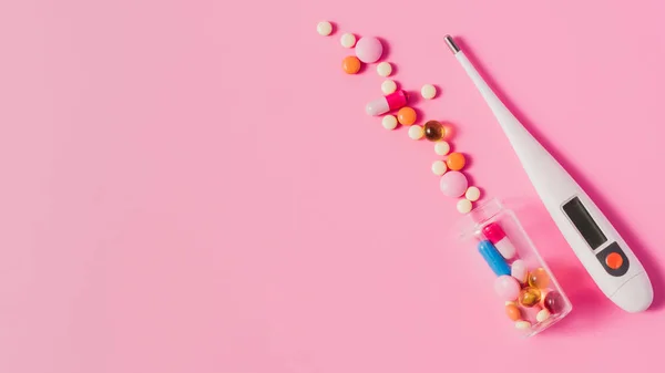 Top view of various different pills from bottle and electric thermometer on pink — Stock Photo