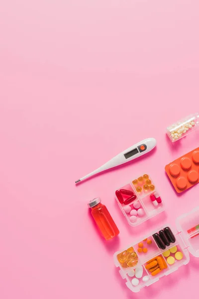 Top view of different medicines and electric thermometer on pink — Stock Photo