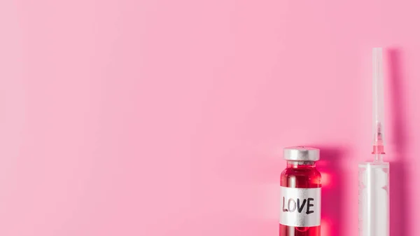 Top view of syringe and bottle with love vaccine sign on pink tabletop — Stock Photo