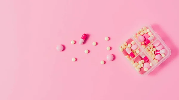 Vista dall'alto della custodia in plastica con varie pillole sul rosa — Foto stock