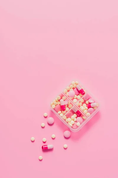 Vista superior del recipiente de plástico con varias píldoras en rosa - foto de stock