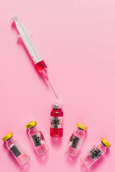 Top view of syringe and bottles with love vaccine signs on pink — Stock Photo