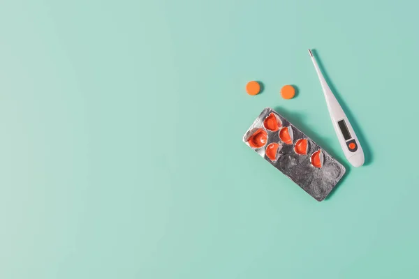 Top view of heap of pills with blister and thermometer on blue — Stock Photo