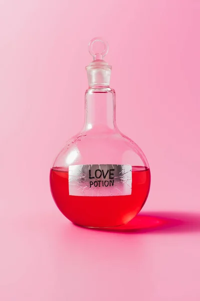 Plan rapproché de la fiole avec potion d'amour de couleur rouge sur rose — Photo de stock