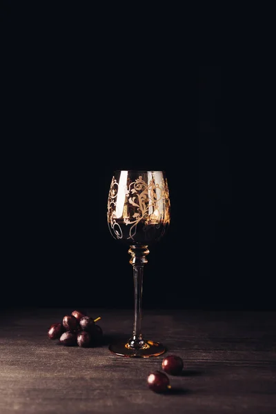 Verre de délicieux vin rouge et raisins frais sur table en bois sur fond noir — Photo de stock