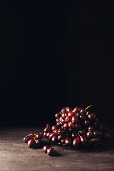 Close-up view of delicious ripe red grapes on wooden table on black — Stock Photo