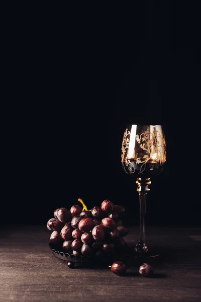 Köstliche reife Trauben und ein Glas Rotwein auf einem Holztisch auf schwarz — Stockfoto