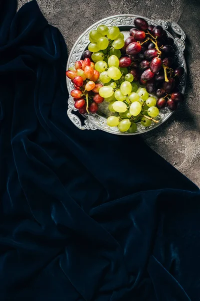 Вид сверху на винтажную пластину с различными видами винограда и темную ткань с копировальным пространством — стоковое фото