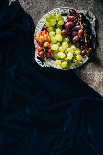 Vista superior de la placa vintage con varios tipos de uvas y tela oscura con espacio de copia - foto de stock