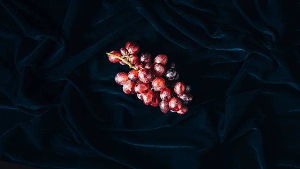 Vista superior de uvas vermelhas maduras frescas em tecido escuro — Fotografia de Stock