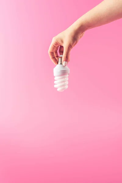 Primo piano vista parziale della persona che tiene lampadina isolata su rosa — Foto stock