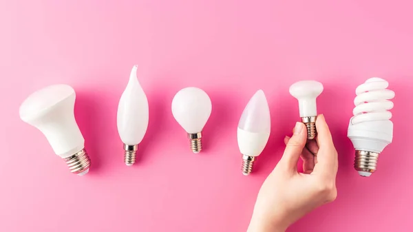 Plan recadré de la main humaine et divers types d'ampoules sur rose — Photo de stock