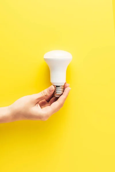 Primo piano vista parziale di persona che tiene lampadina su giallo — Foto stock