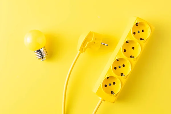 Vista superior de la toma de corriente amarilla, enchufe y bombilla en amarillo - foto de stock