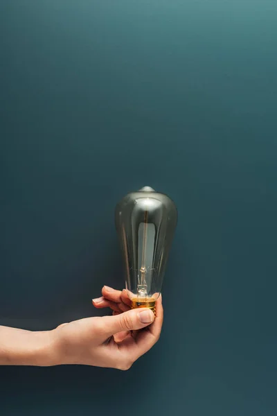 Cropped shot of person holding light bulb on grey background — Stock Photo
