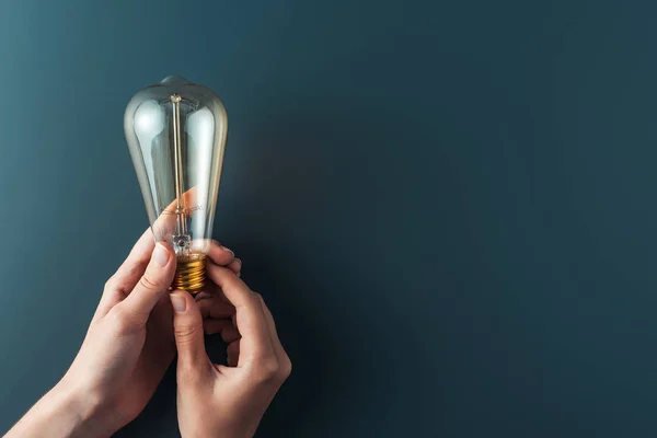 Close-up partial view of person holding light bulb on grey background — Stock Photo