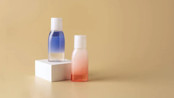 Close up view of face wash in bottles on white cube on beige backdrop — Stock Photo