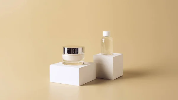 Close up view of micellar water and body cream on white cubes on beige background — Stock Photo