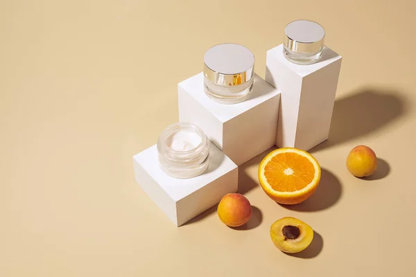 Vista de cerca de las cremas y frutas dispuestas para el cuidado de la piel sobre fondo beige - foto de stock