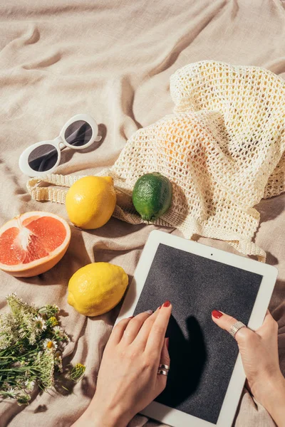 Plan recadré de la personne en utilisant tablette numérique et sac à ficelle avec des fruits frais et des lunettes de soleil — Photo de stock