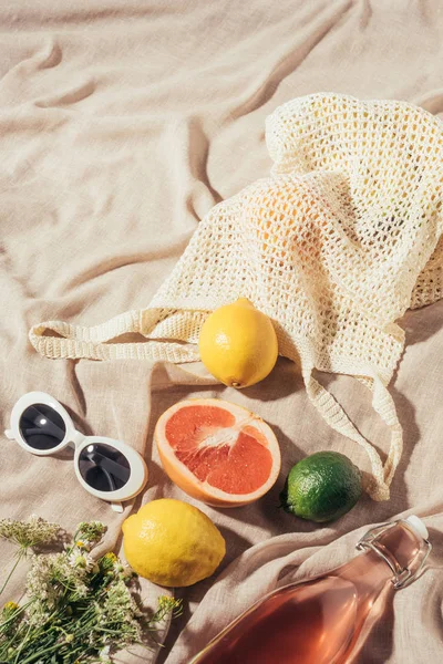 Vista de cerca de gafas de sol, flores, botella de vidrio con bebida de verano y frutas tropicales frescas - foto de stock