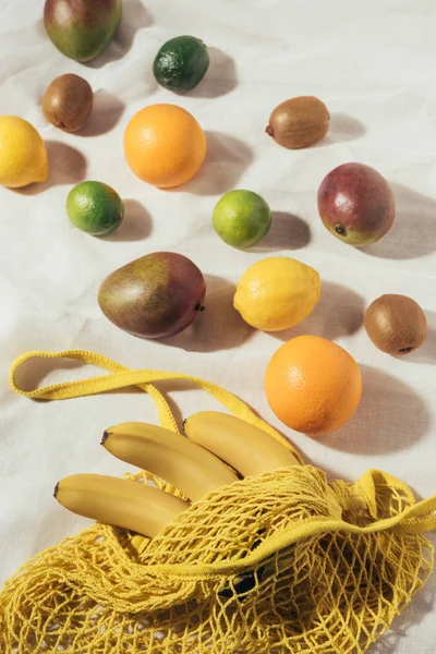 High angle view of yellow string bag and fresh ripe tropical fruits — Stock Photo