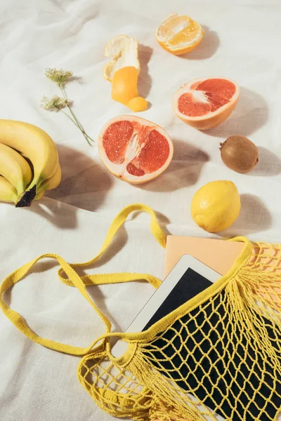 Computador tablet em saco de corda amarela e frutas tropicais maduras frescas — Fotografia de Stock