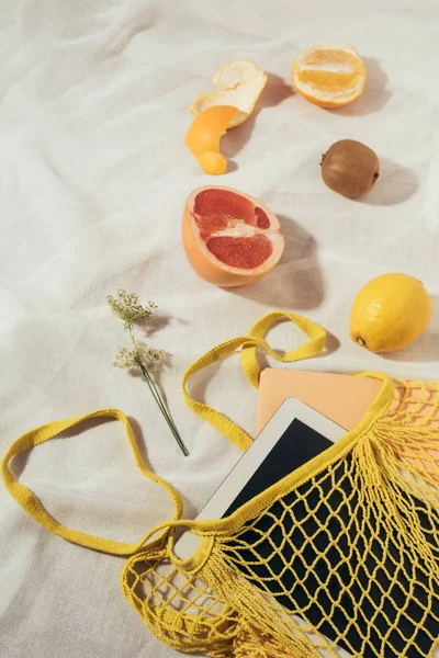 Ansicht von Tablet-Computer in gelbem Saitensack und frischen reifen tropischen Früchten — Stockfoto