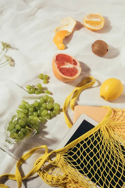 Top view of string bag with digital tablet and fresh ripe fruits — Stock Photo