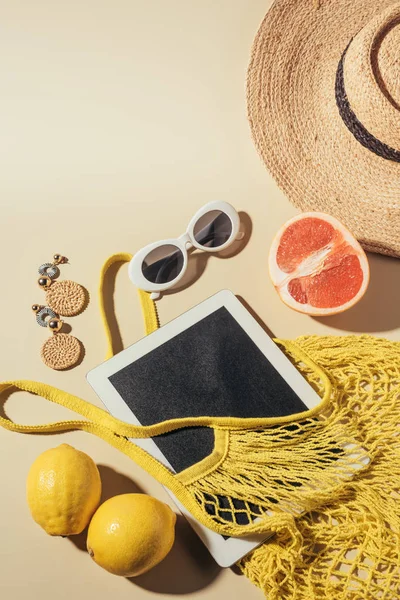 Vista superior de la tableta digital, gafas de sol, sombrero y bolsa de hilo con frutas - foto de stock