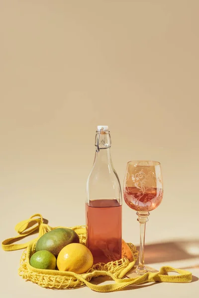 Vista de cerca de la bebida en vidrio y botella, bolsa de cuerda y frutas frescas en marrón — Stock Photo