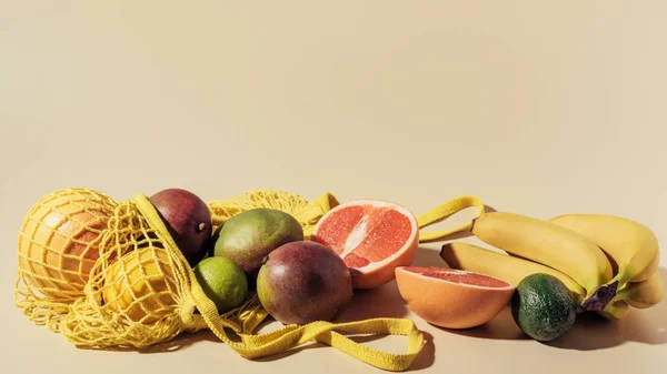 Close-up view of fresh ripe fruits and string bag on brown — Stock Photo
